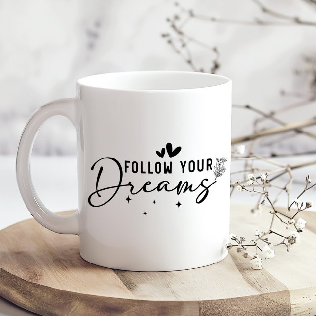 Taza de café con letra floral "Sigue tus sueños" (Follow Your Dreams Floral Script Coffee Mug on a kitchen table with tiny dry flowers)