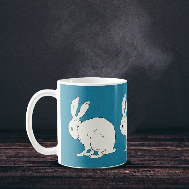 Taza De Café conejos elegantes sentados blancos en azul (Simple white sitting rabbits on dark blue circling a coffee or tea mug.)