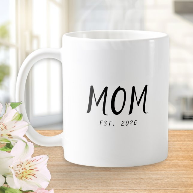 Taza de café de regalo para mamá establecida (A white coffee mug with customizable words "Mom Est. 2026" in black text)