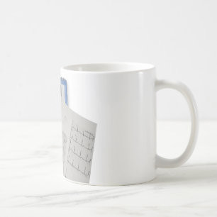 Taza De Café estetoscopio médico en lecturas del cardiograma