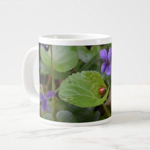 Taza De Café Gigante Ladybug sobre las dulces flores violetas