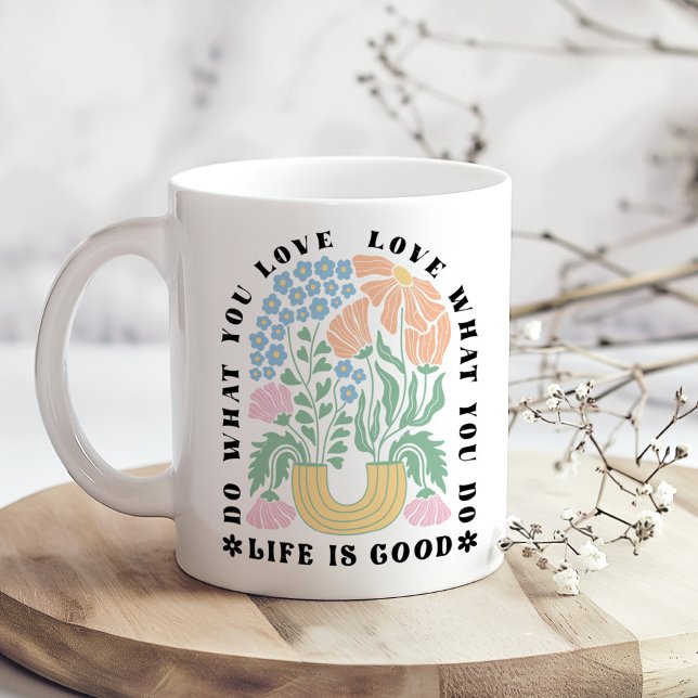 Taza De Café "Haz lo que amas" Arco Floral Retro ("Do What You Love" Retro Floral Arch Coffee Mug on a boho wooden kitchen table next to dry flowers.)