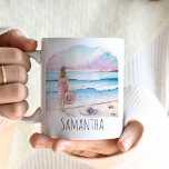 Taza De Café La vida es mejor en la playa Personalizada<br><div class="desc">Estas hermosas tazas de café personalizadas presentan un diseño sereno de acuarela de una mujer de pie junto a la orilla, sosteniendo un gorra de playa, con suaves tonos rosas y azules que evocan una serena escena oceánica. Las palabras "La vida es mejor en la playa" están elegantemente inscritas en...</div>