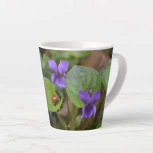 Taza De Café Latte Ladybug sobre las dulces flores violetas