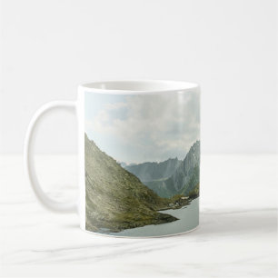 TAZA DE CAFÉ MONTAÑAS VERDES Y MARRÓN CERCA DEL CUERPO DE AGUA