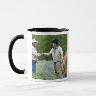 Taza Ganaderos dándose la mano a través de la cerca en