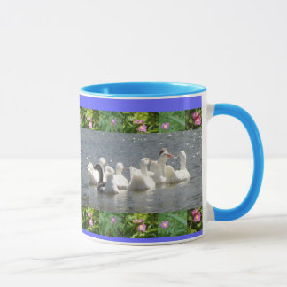 Taza gansos en el agua con la frontera floral