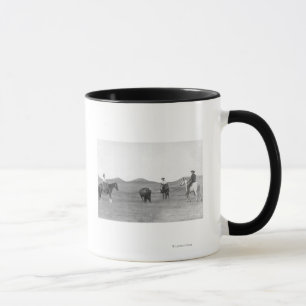Taza Vaqueros en caballos dándole una foto de búfalo