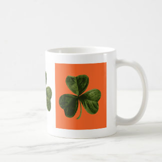 Taza verde, blanca y anaranjada del trébol