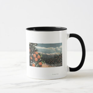 Taza Vista de una huerta anaranjada con las montañas