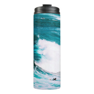 Termo Persona en tabla de surf con olas oceánicas