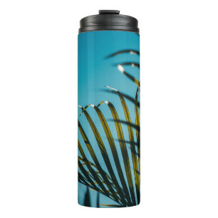 Termo Plantas verdes de palma bajo cielo azul por la mañ