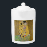 Tetera El abrazo del beso de los amantes por Gustav Klimt<br><div class="desc">La luz del sol brilla por el agitado abrazo dorado que rodea a los amantes de la obra maestra de Gustav Klimt, The Kiss. La escena es una paradoja de intimidad y aislamiento. La pareja está parada en un precipicio, un campo de flores coloridas a sus pies, sin embargo, son...</div>