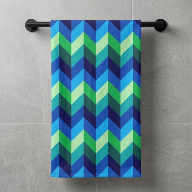 Toalla de baño con chevrones ombré azul verde (Blue Green Ombre Chevrons Bath Towel hanging on a towel rod against a wall in modern style bathroom.)