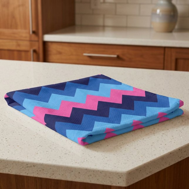 Toalla de cocina con patrón de chevron azul rosa (Cool Blue Pink Chevron Pattern Kitchen Towel folded on a counter in a kitchen.)