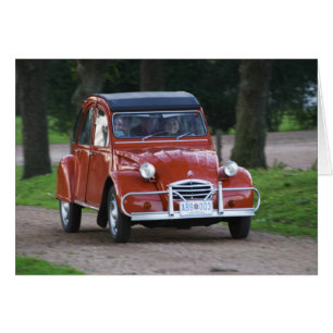 Un viejo coche rojo Citroen 2CV con una mujer sonr