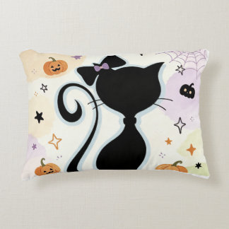 Una almohada linda y un gato negro.