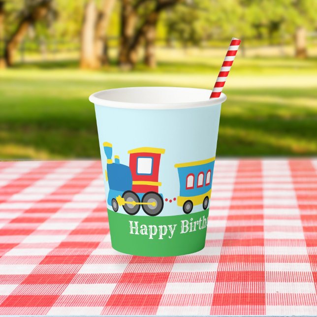Vasos De Papel Cute Train Birthday Party (A paper cup decorated with a cute cartoon train sits on a picnic table in a park.)