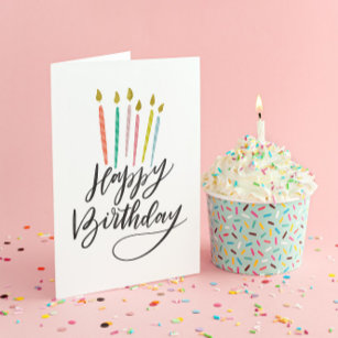 Velas coloridas con tarjeta de cumpleaños feliz