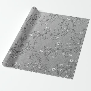 Vid floral blanca sobre papel de regalo plateado